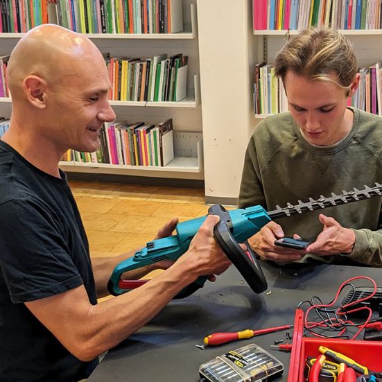 To frivillige i bibliotekets Repair Cafe reparerer en hæksaks