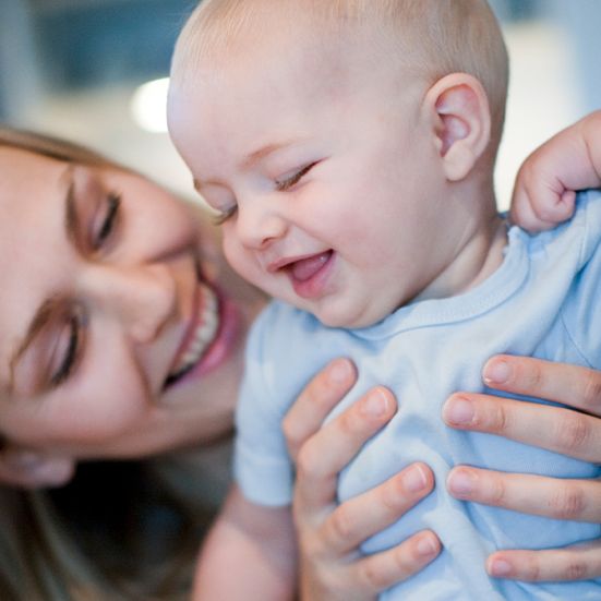 Glad mor holder smilende baby