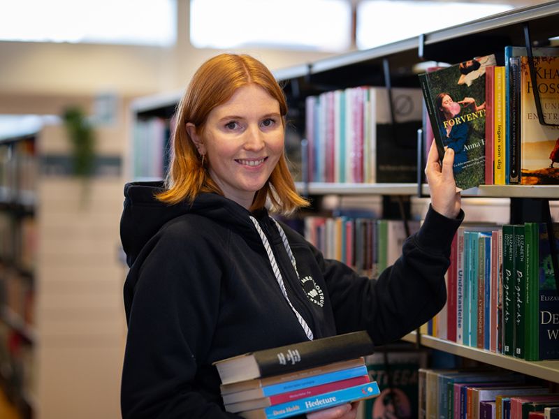 Bibliotekets litteraturformidler Mette tager en bog fra hylden
