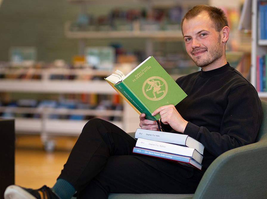Bibliotekets litteraturformidler Stinus sidder med bogen "De græske myter"